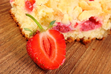 Fresh baked yeast cake with strawberries on wooden table