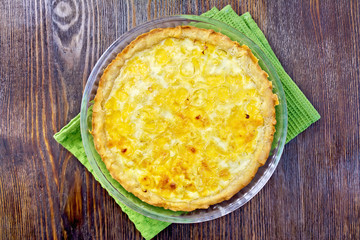 Pie with cheese and leek in glass pan on board