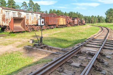 Fototapeta na wymiar Railway switch with old rusty waggonage with steam locomotive, carriage and wagon in background. 