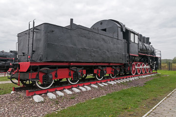 Fototapeta na wymiar Old black steam locomotive on cloudy sky background 