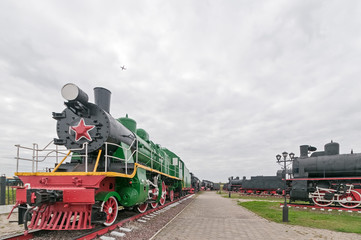Fototapeta na wymiar Old black steam locomotive on cloudy sky background 