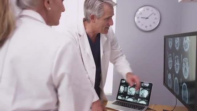 Mature male radiologist and assistant doctor looking at xrays