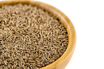 Macro of whole cumin seeds in bowl with copyspace