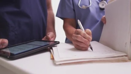 Close-up of mature female nurse writing in a patient's folder - Powered by Adobe
