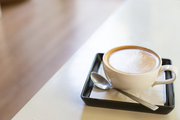 Hot art Latte Coffee in a cup and laptop on wooden table.