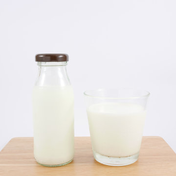 The glass and bottle of fresh milk on the wooden board.