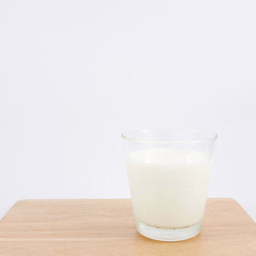 The glass of fresh milk on the wooden board.