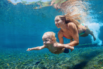 Happy family - mother with baby boy dive underwater with fun in sea pool. Healthy lifestyle, active...