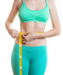 Fit and healthy young woman measuring her waist with a tape measure Isolated on white.