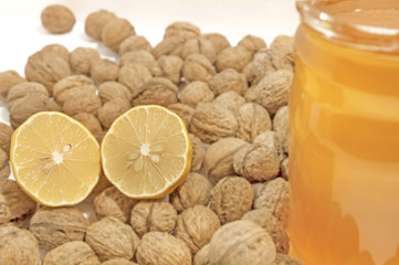 Lemon cut close on white table with honey jar and walnuts  isola