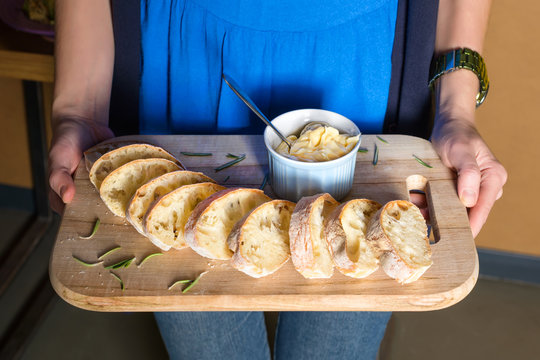 Server holding wooden tray with freshly baked bread and homemade butter. Women's hands with wooden server of appetizers.