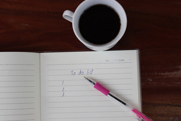 To do list  with a pen and cup of fresh coffee on wood background