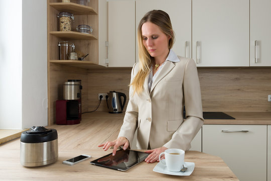 Modern business woman with tablet and coffee in the kitchen