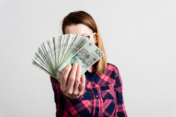 Kobieta trzyma plik polskich pieniędzy przed sobą - obrazy, fototapety, plakaty