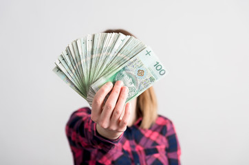 Kobieta trzyma plik polskich pieniędzy przed sobą