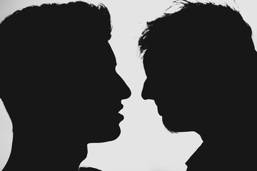Silhouette of two men about to kiss