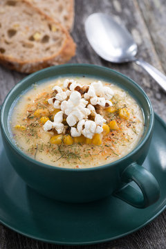 corn soup with popcorn in ceramic cup on wooden table, vertical
