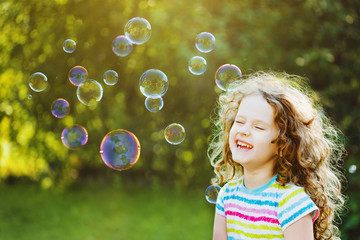 Laughing curly girl with bubbles.