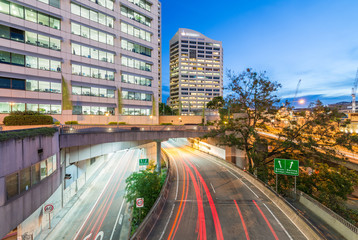 Fototapeta na wymiar Light trails of cars speeding up along modern city