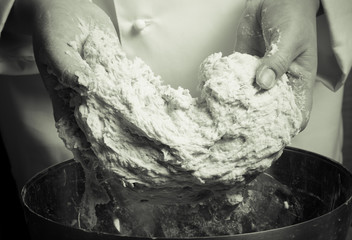 Woman's hands knead dough. Selective focus. Toned