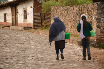 Una se&ntilde;ora y una ni&ntilde;a caminan por una carretera empedrada.