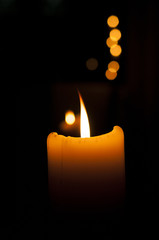 lit candle with the flame burning in the dark.