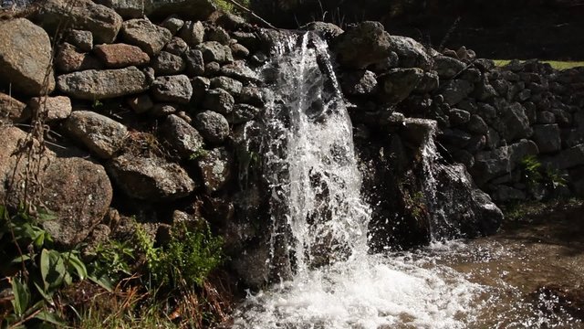 Salto de agua de gran caudal pasando a través de un muro de piedra