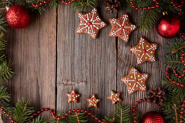 Gingerbread star cookies composition in fir tree decorations frame on vintage wooden table background. Empty space for designer text. Top view. Traditional homemade holiday recipe