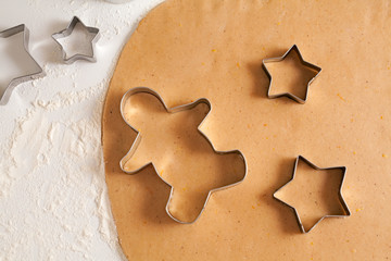 Homemade traditional gingerbread cookies dough preparation recipe on white kitchen table with cutting forms and flour