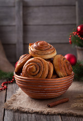 Sweet cinnamon bun rolls or kanelbullar christmas homemade norwegian delicious sweet dessert with spice on vintage woonde table. Traditional swedish baked pastry