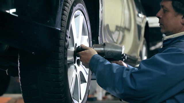 Mechanic unscrews the bolts out of the wheel