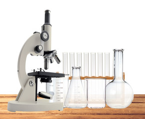 Laboratory metal microscope and test tubes on wooden table isola