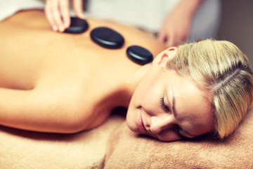 Obraz na płótnie Canvas close up of woman having hot stone massage in spa