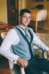 Businessman in a waistcoat and plastron sitting on a chair in the interior Suites