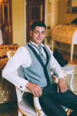 Businessman in a waistcoat and plastron sitting on a chair in the interior Suites