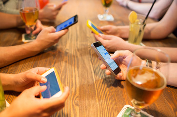 close up of hands with smartphones at restaurant