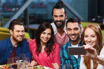 friends taking selfie by smartphone at restaurant