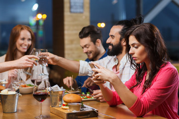 woman with smartphone and friends at restaurant