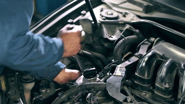 Mechanic fastens detail of car engine