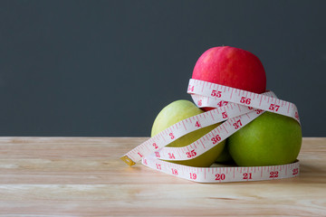 Green apple core and measuring tape. Diet concept with copy space on grey background 