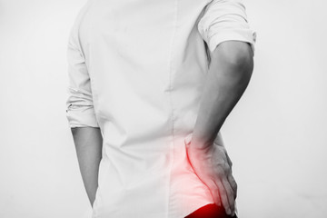 Young man in casual office shirt having hip pain (Selective Focus) - obrazy, fototapety, plakaty