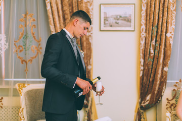 groom holding champagne glasses