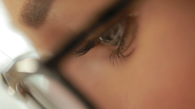 Close-up shot of woman's eyes in glasses. Young woman with glasses drawing sketches for clothes.