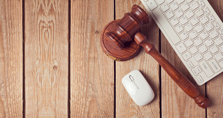 Law gavel and keyboard on wooden background. Online law enforcement concept. View from above