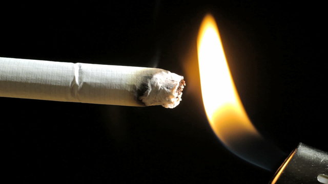 Cigarette on a black background, lighter and smoke