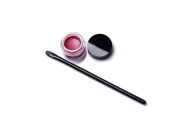 Red lip gloss in jar with makeup brush