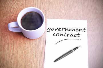 Coffee on the table with note writing government contract