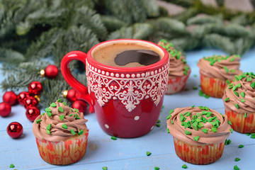Red mug with coffee and Christmas cupcakes with chocolate cream