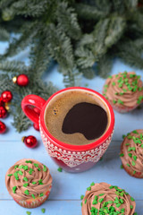 Red mug with coffee and Christmas cupcakes with chocolate cream,