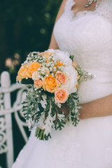 Bride holds a beautiful wedding bouquet of orange roses